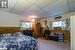 Carpeted bedroom with a paneled ceiling, white refrigerator, wooden walls, and baseboard heating