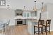 Kitchen with gray cabinetry, hanging light fixtures, light hardwood / wood-style floors, and stainless steel appliances