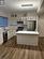 Kitchen with white cabinets, stainless steel appliances, hanging light fixtures, and dark wood-type flooring