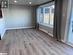 Kitchen featuring sink, an AC wall unit, dark stone countertops, a kitchen island with sink, and light wood-type flooring