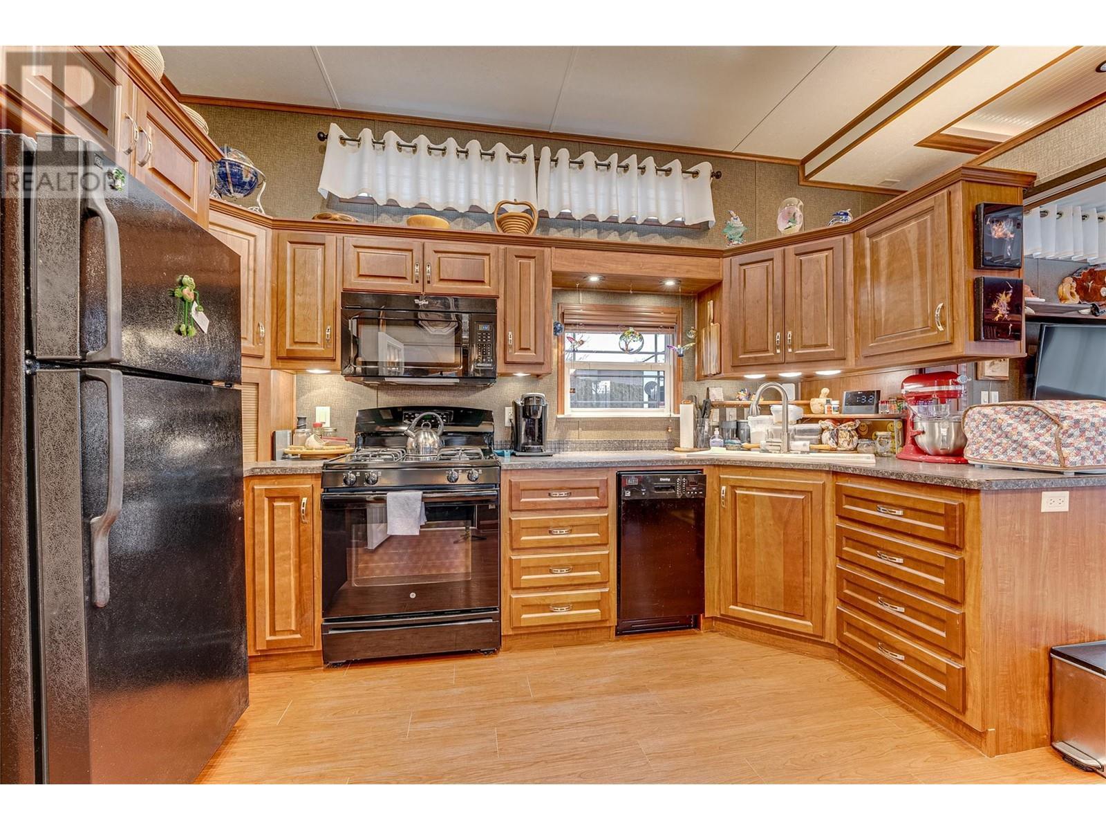Large open kitchen with black appliances and gas stove - 8000 Highland Road Unit# 42, Vernon, BC - Indoor Photo Showing Kitchen