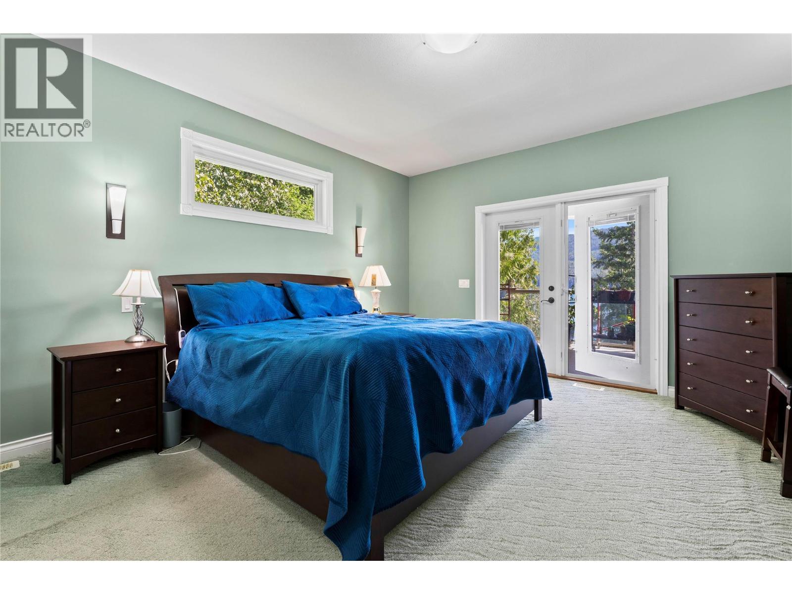 Primary Bedroom with a lake view & deck access - 8738 Squilax Anglemont Road, St. Ives, BC - Indoor Photo Showing Bedroom