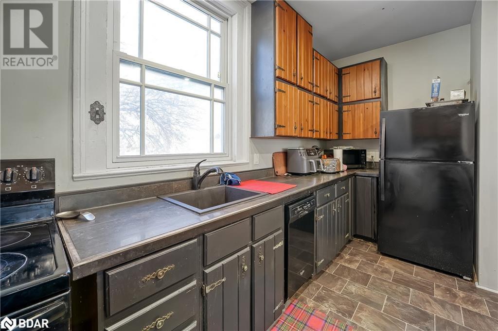 Kitchen featuring stone finish floor, a sink, black appliances, and dark countertops - 7369 5Th Sideroad Side Road, Adjala-Tosorontio, ON