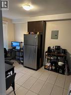 Kitchen with freestanding refrigerator, electric panel, a desk, dark brown cabinets, and light tile patterned floors -