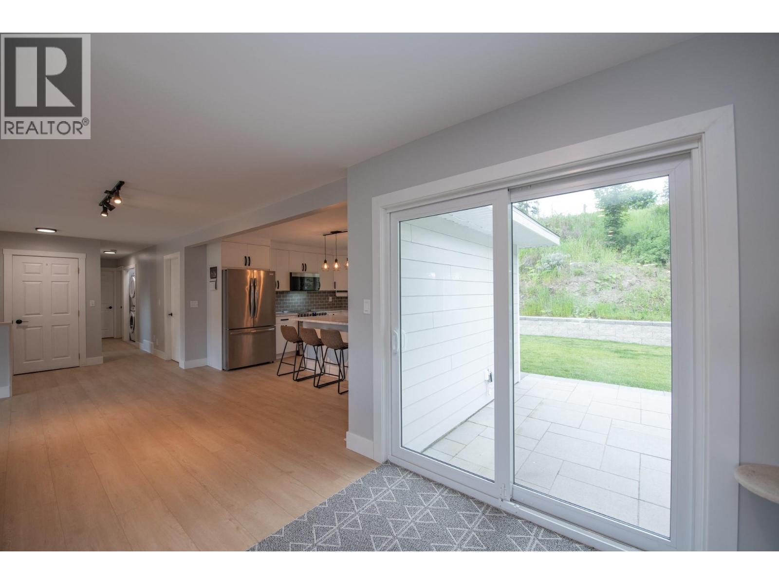 Out to concrete slab patio and beautiful back yard - 2224 Linea Crescent, Lumby, BC - Indoor Photo Showing Other Room