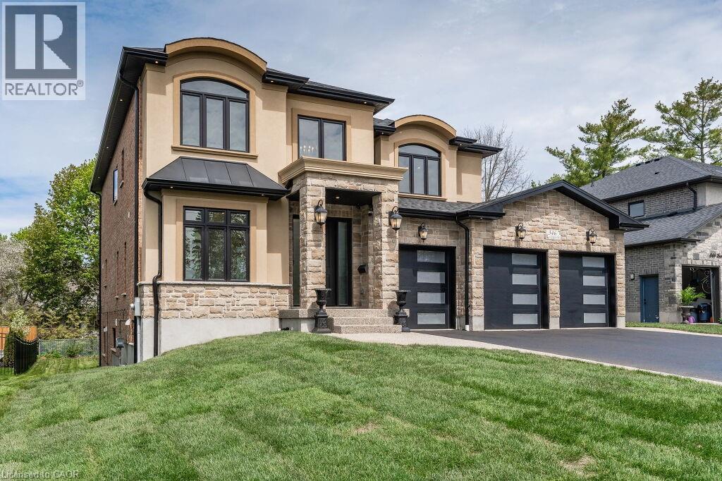 View of front of house featuring stone siding, a front lawn, stucco siding, driveway, and a standing seam roof - 346 Lexington Road, Waterloo, ON - Outdoor With Facade