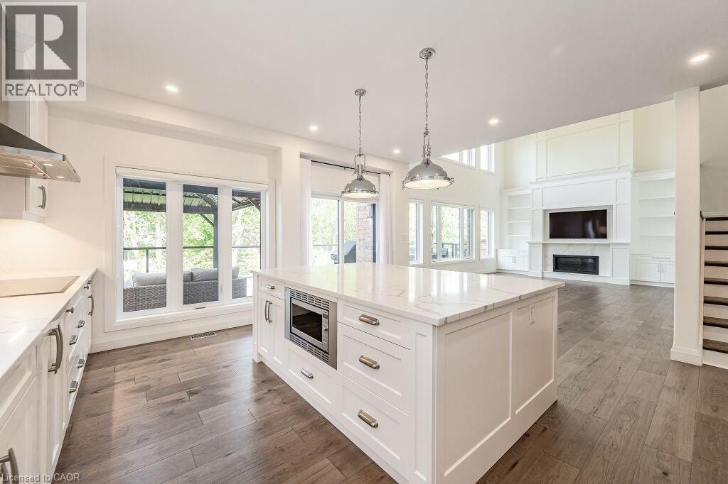 Kitchen with stainless steel microwave, recessed lighting, black electric cooktop, dark wood-style floors, and a glass covered fireplace - 346 Lexington Road, Waterloo, ON - Indoor Photo Showing Kitchen With Upgraded Kitchen