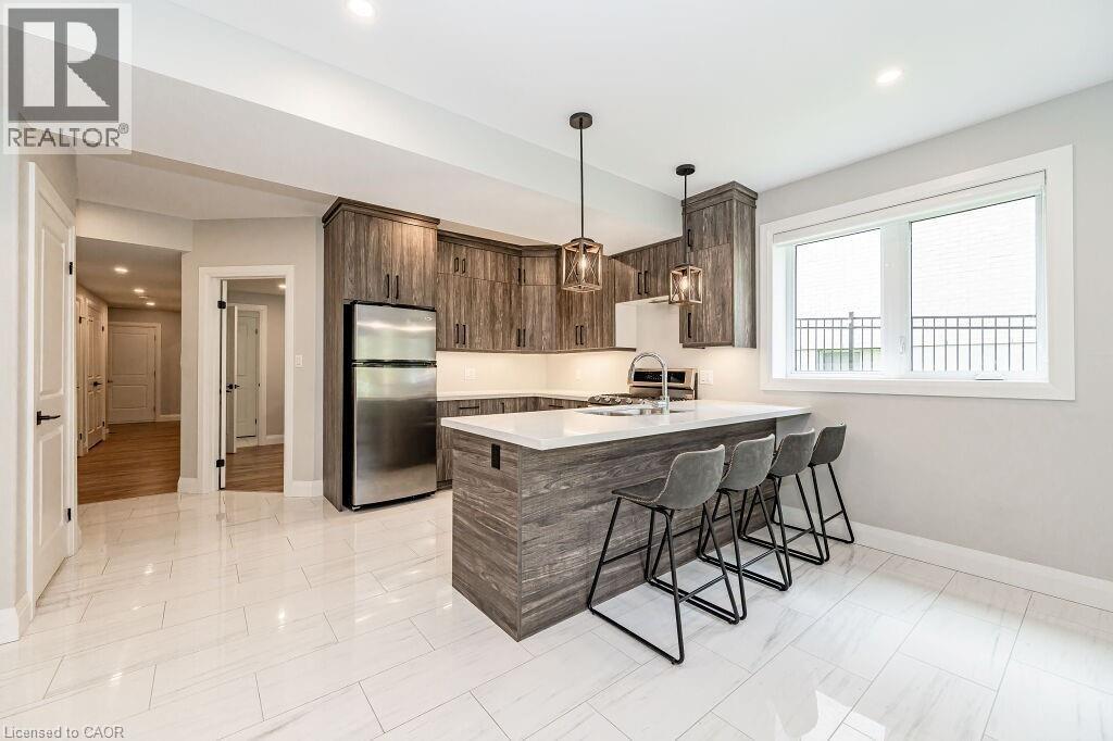 Kitchen featuring freestanding refrigerator, baseboards, a sink, a kitchen bar, and light countertops - 346 Lexington Road, Waterloo, ON - Indoor Photo Showing Kitchen