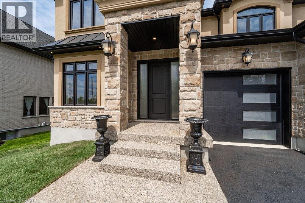 View of exterior entry with stone siding, a standing seam roof, asphalt driveway, and metal roof - 346 Lexington Road, Waterloo, ON - Outdoor With Facade