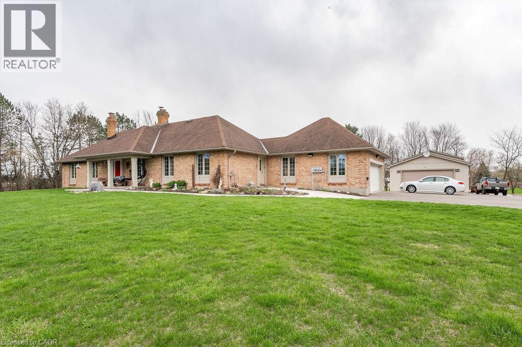 Ranch-style home with a chimney, a front lawn, brick siding, covered porch, and a garage - 4290 Victoria Road S, Puslinch, ON - Outdoor