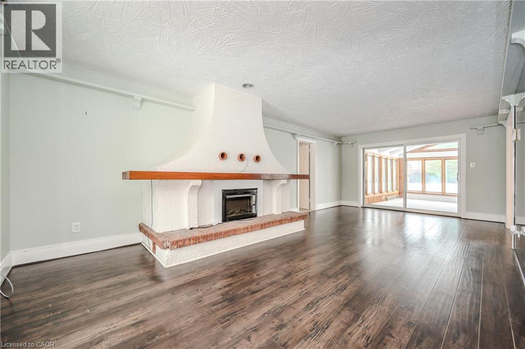 Unfurnished living room featuring wood finished floors, a brick fireplace, and a textured ceiling - 4290 Victoria Road S, Puslinch, ON - Indoor Photo Showing Living Room With Fireplace