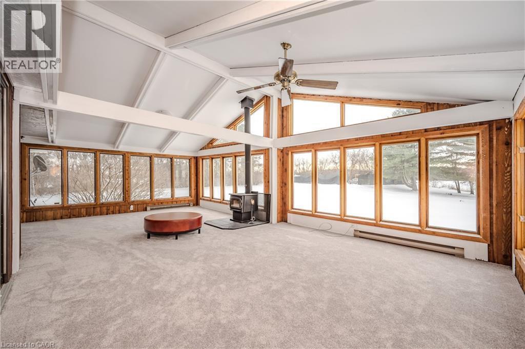 Unfurnished sunroom with a baseboard heating unit and a wood stove - 4290 Victoria Road S, Puslinch, ON - Indoor Photo Showing Other Room