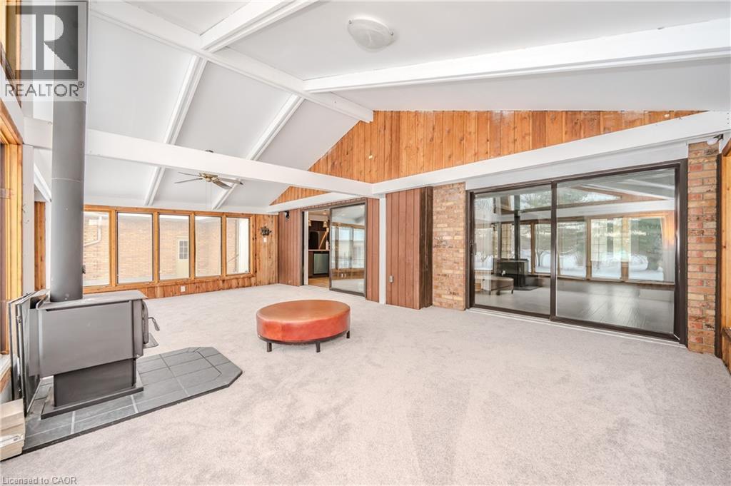 Living room with carpet flooring, a wood stove, a ceiling fan, and wood walls - 4290 Victoria Road S, Puslinch, ON