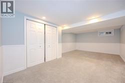 Finished basement with light colored carpet, wainscoting, and recessed lighting -