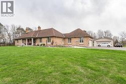 Ranch-style home with a chimney, a front lawn, brick siding, covered porch, and a garage -
