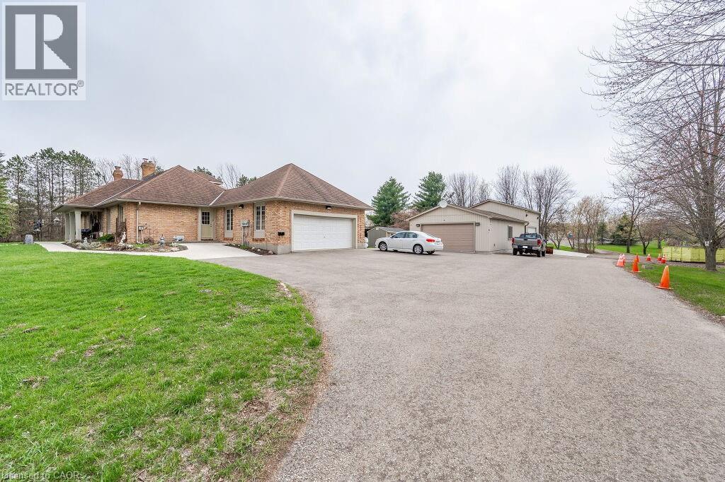 View of front of home with a chimney, a front yard, brick siding, and a garage - 4290 Victoria Road S, Puslinch, ON