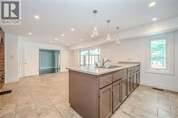 Kitchen featuring healthy amount of natural light, light countertops, recessed lighting, pendant lighting, and gray cabinetry -