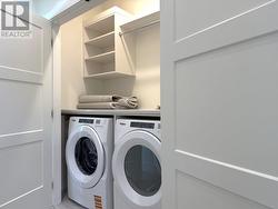 Laundry room with full sized washer and dryer, tiled floor and countertops and shelving -