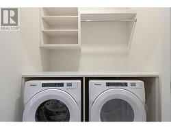 Laundry room with full sized Whirlpool washer/dryer, countertops, shelving and sensor lighting. -