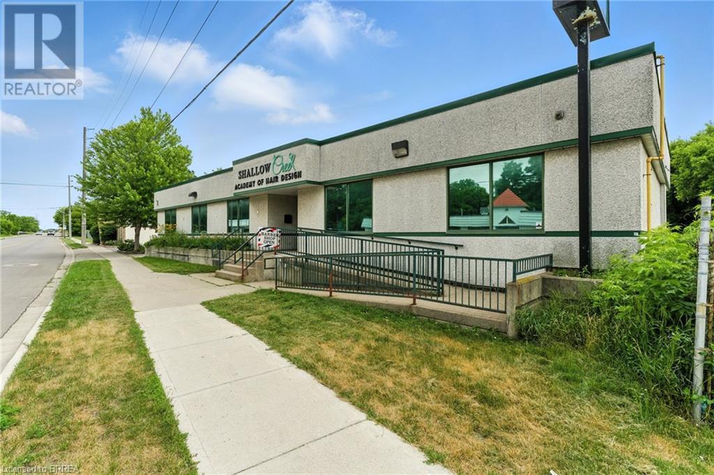 View of front of house with stucco siding and a front lawn - 207 Greenwich Street, Brantford, ON