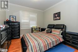 Bedroom with hardwood / wood-style floors and crown molding -