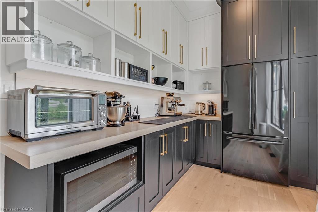 Kitchen with high quality fridge, stainless steel microwave, open shelves, light wood-style flooring, and light countertops - 4678 Lobsinger Line, Crosshill, ON - Indoor Photo Showing Kitchen