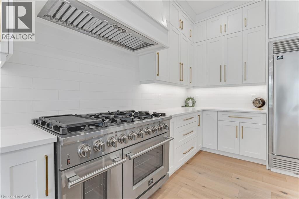 Kitchen featuring high end appliances, premium range hood, tasteful backsplash, light countertops, and white cabinets - 4678 Lobsinger Line, Crosshill, ON - Indoor Photo Showing Kitchen With Upgraded Kitchen