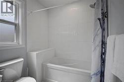 Bathroom with shower / bath combination with curtain and toilet -