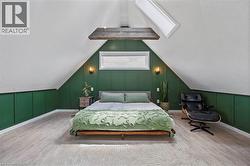Bedroom with a decorative wall, wood finished floors, vaulted ceiling, and a skylight -