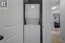 Washroom with stacked washing machine and dryer and light wood finished floors -