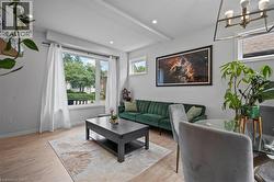 Living area with wood finished floors, beamed ceiling, a chandelier, and recessed lighting -