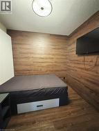 Bedroom with wooden walls, wood finished floors, and a textured ceiling -