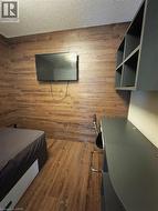 Bedroom featuring a textured ceiling, wood finished floors, and wood walls -