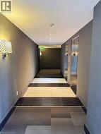 Hallway featuring tile patterned floors, elevator, and baseboards -