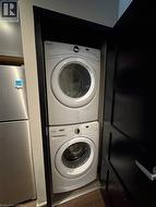 Clothes washing area featuring stacked washing machine and dryer -