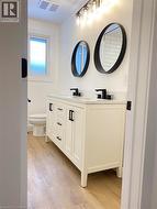 Bathroom with double vanity and wood finished floors -