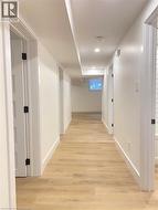 Hallway with light wood finished floors and recessed lighting -
