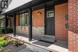 Doorway to property with brick siding, a porch, and stone siding -