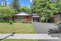 View of front facade with a garage, driveway, a front lawn, and brick siding -