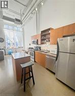 Kitchen with appliances with stainless steel finishes, a center island, a high ceiling, tasteful backsplash, and open shelves -