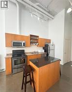 Kitchen with a high ceiling, appliances with stainless steel finishes, decorative backsplash, a center island, and open shelves -