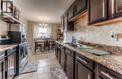 Kitchen featuring stainless steel range with electric stovetop, dark brown cabinets, a chandelier, and a textured ceiling -