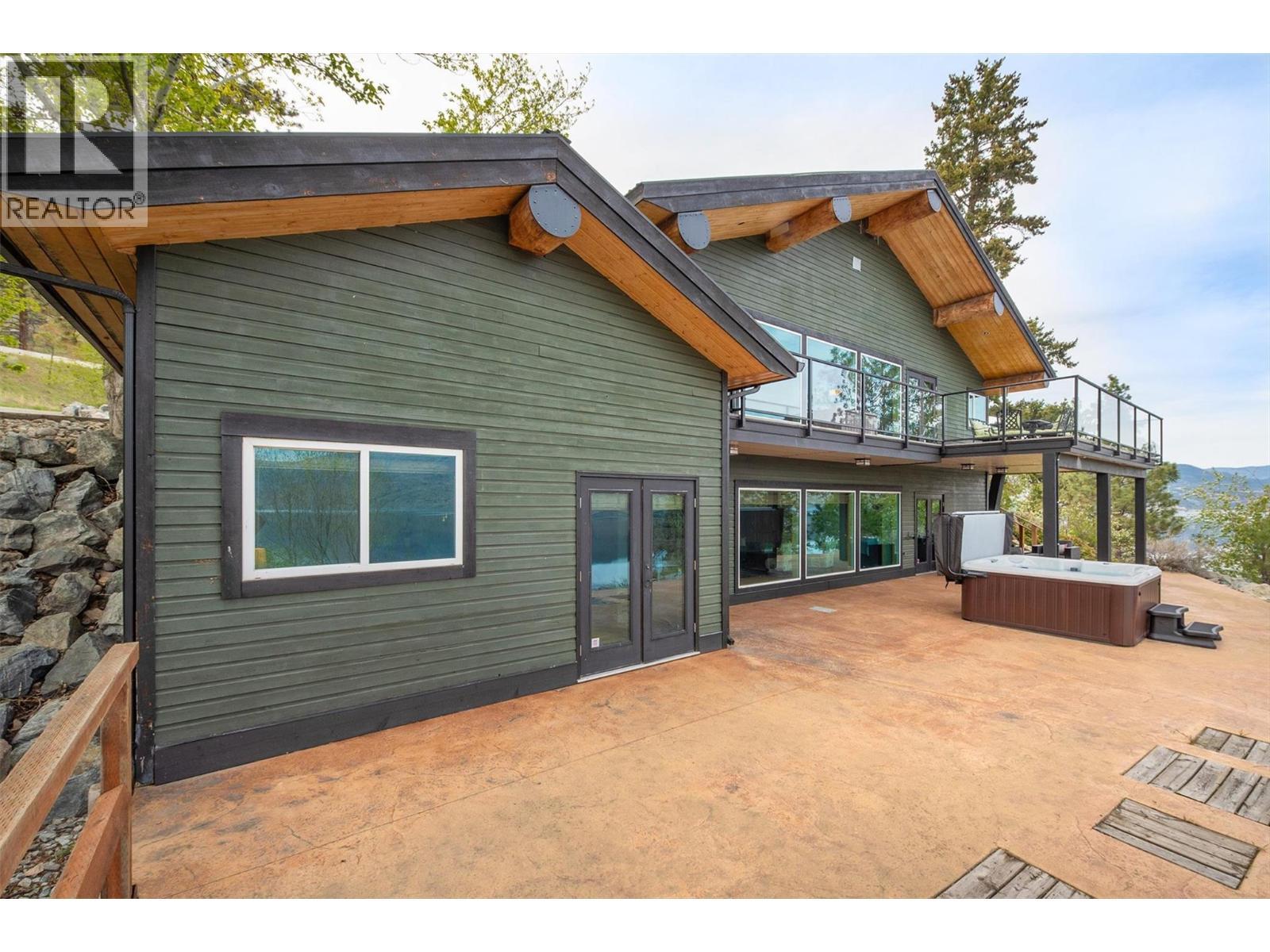 Spacious patio with hot tub and views just off of the lower level games room. - 7172 Brent Road, Peachland, BC - Outdoor With Deck Patio Veranda With Exterior