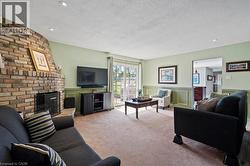 Living room with a decorative wall, a brick fireplace, a textured ceiling, carpet flooring, and wainscoting -