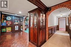 Bar area featuring arched walkways, a textured ceiling, wooden walls, wainscoting, and glass insert cabinets -