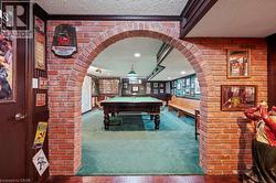 Rec room featuring arched walkways, carpet flooring, pool table, a textured ceiling, and brick wall -