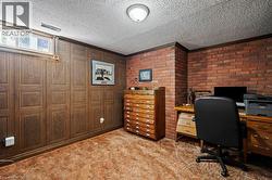Home office featuring dark carpet and a textured ceiling -