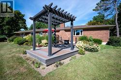 View of grassy yard with a deck and a pergola -