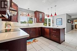 Kitchen featuring light stone counters, a peninsula, decorative light fixtures, glass insert cabinets, and recessed lighting -