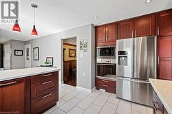 Kitchen with stainless steel appliances, pendant lighting, recessed lighting, light tile patterned floors, and light stone countertops -